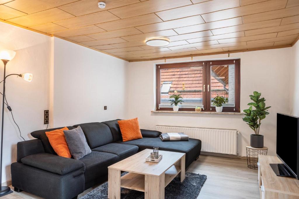 Una sala de estar con un sofá negro y una mesa. en Ferienwohnung Hennen, en Witzenhausen