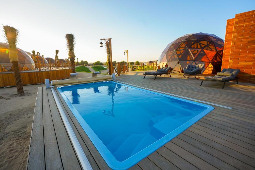 einen Pool auf einer Terrasse mit zwei Kuppeln in der Unterkunft Al Marmoom Oasis Luxury Experiential Desert Domes in Dubai