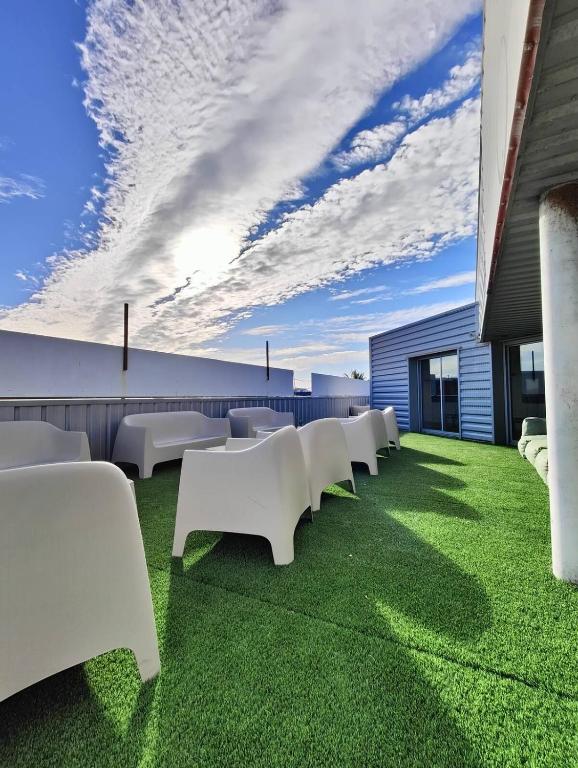une rangée de tables et de chaises blanches sur une pelouse dans l'établissement Loft 155 séjour famille spacieux jeux terrasse, à Castelnau-le-Lez