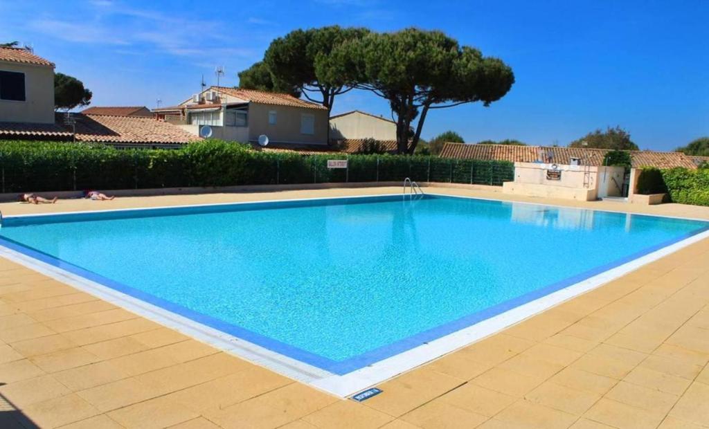 une grande piscine bleue dans une cour dans l'établissement CAP D'AGDE Maison mitoyenne T2 cabine PISCINE PARKING proche village naturiste, au Cap d'Agde