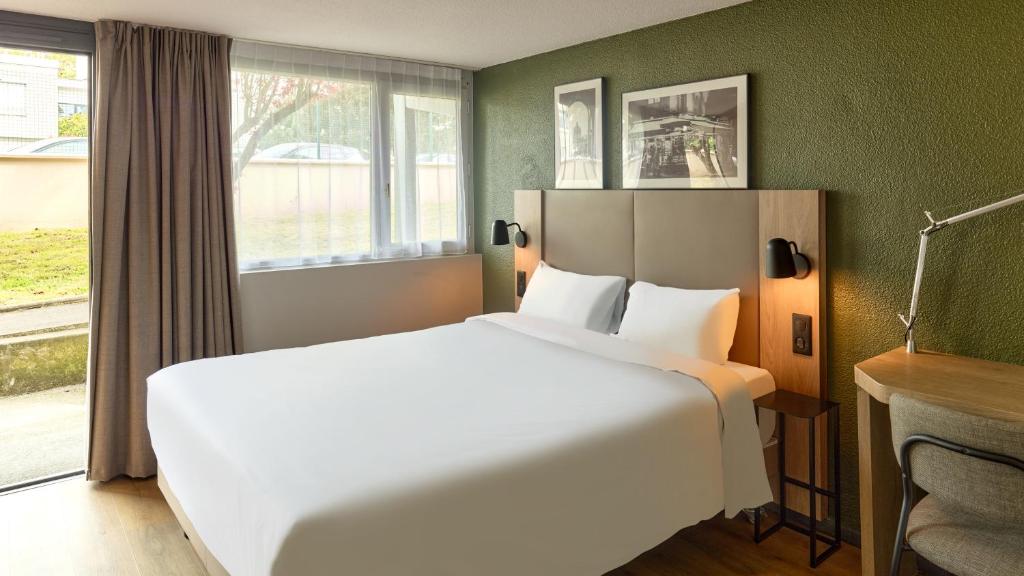 a hotel room with a large bed and a window at Campanile NATURE - Marne La Vallée - Chelles in Chelles