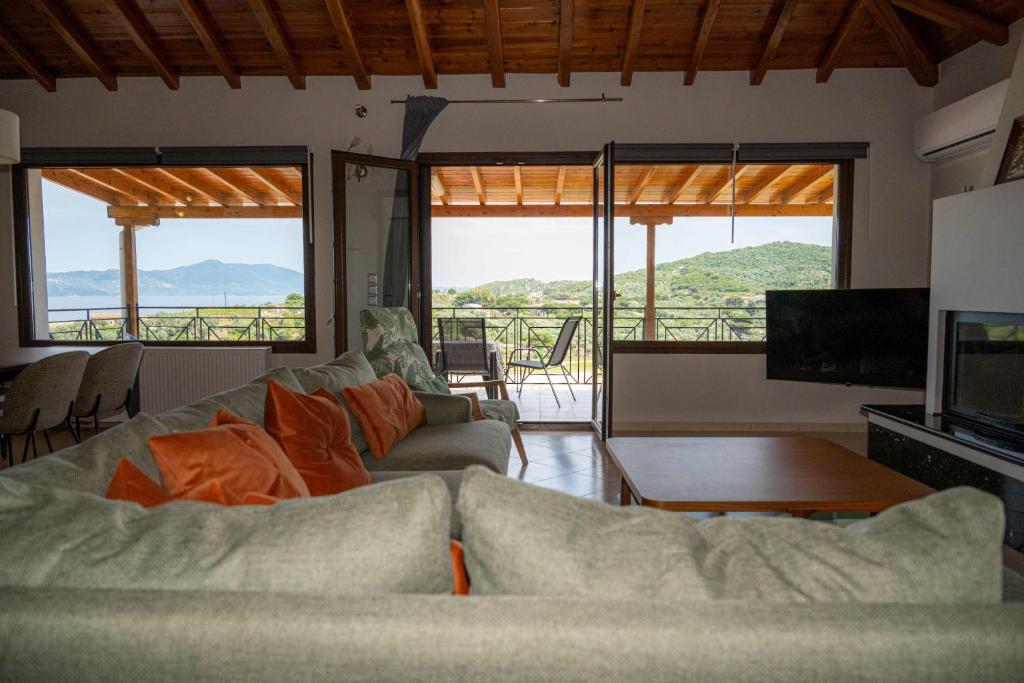 Una sala de estar con un sofá y un televisor y ventanas. en Runway Mansion, stunning views and lots of space, en Skiathos