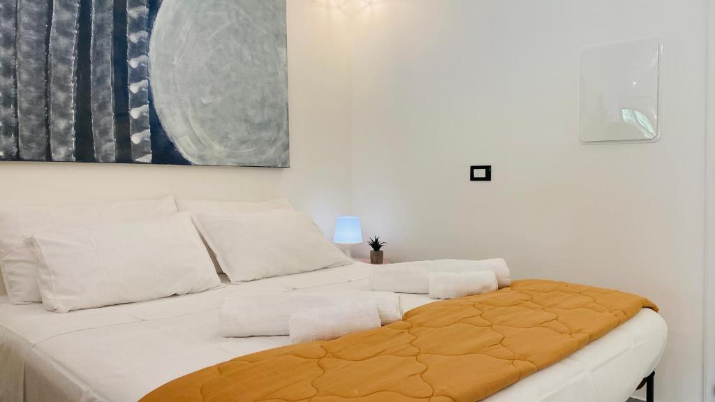 a white bedroom with a bed and a painting at LAC Holiday Apartment in Calceranica al Lago