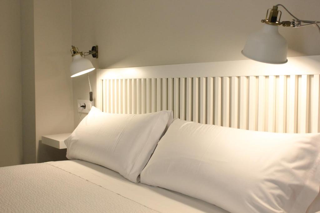 Una cama blanca con dos almohadas encima. en Las Atarazanas - Design Hostal, en Sevilla