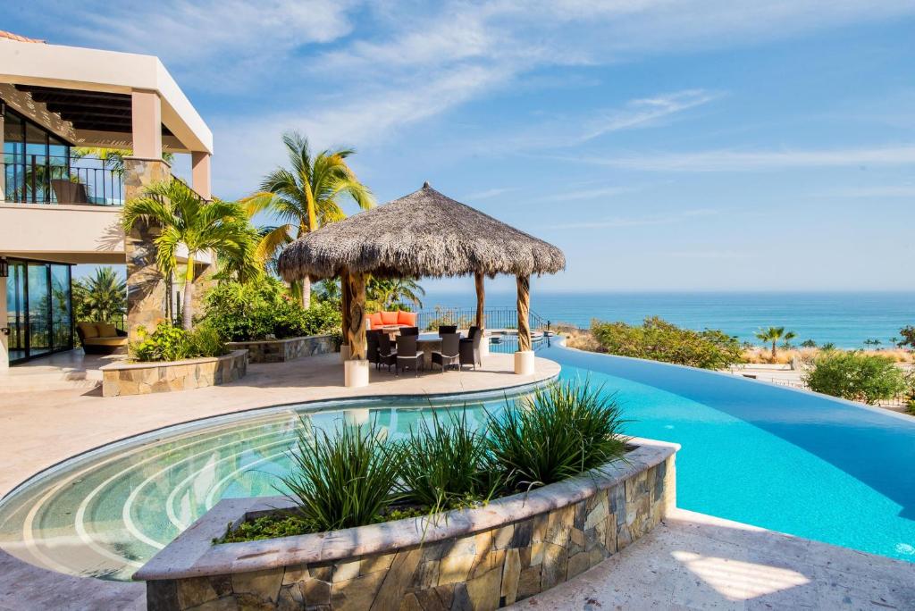 a resort swimming pool with a view of the ocean at Villa de Suenos by Cabo Villas in San José del Cabo