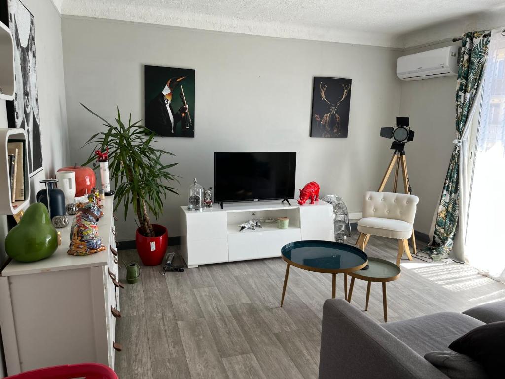 - un salon avec une télévision sur un meuble blanc dans l'établissement Appartement charmant dans une résidence calme, à Perpignan