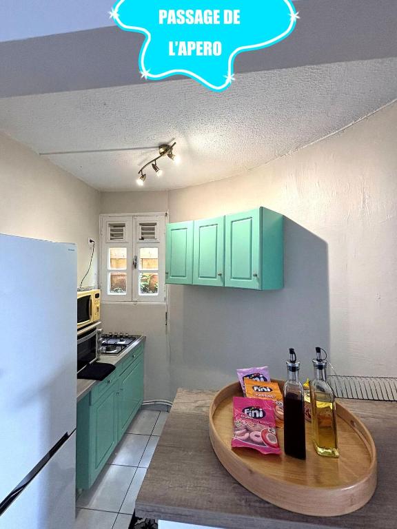 a kitchen with green cabinets and a wooden table at F2 climatisé Piscine Vue Mer et Montagne Pelée Trois-Îlets in Les Trois-Îlets
