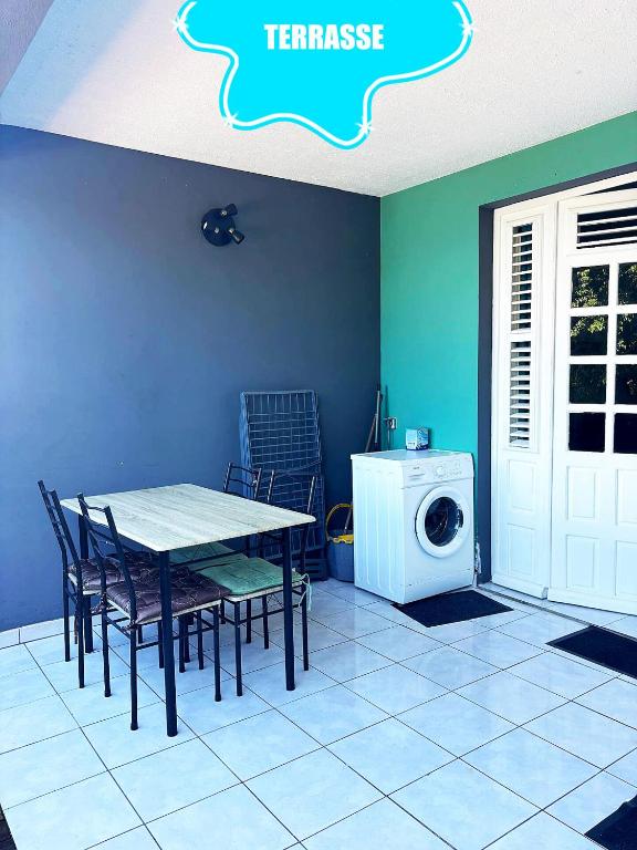 a dining room with a table and a washing machine at F2 climatisé Piscine Vue Mer et Montagne Pelée Trois-Îlets in Les Trois-Îlets