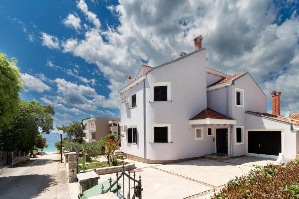 a white house with the ocean in the background at Seaside Apartments Slavica in Petrcane
