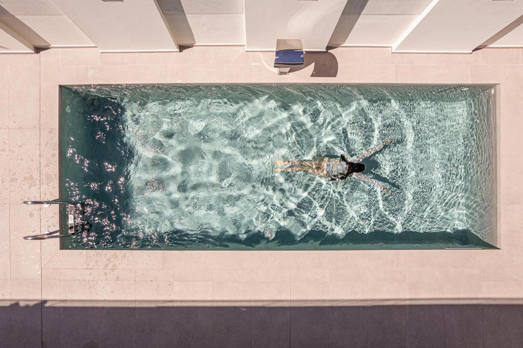 a person swimming in a pool of water at Mossa Concept Villas - heated pool- 200 m from the beach in Daratso