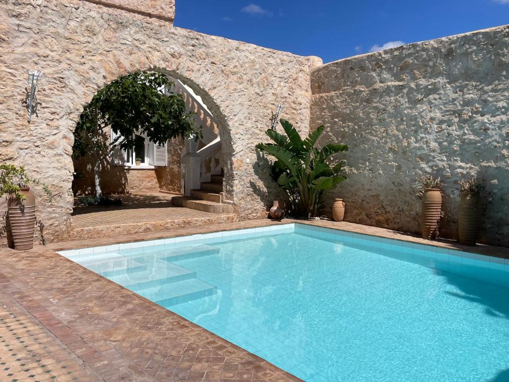 a swimming pool in a building with a stone wall at Superbe ! Riad ALBAYDA Suite & Rooftop in Essaouira