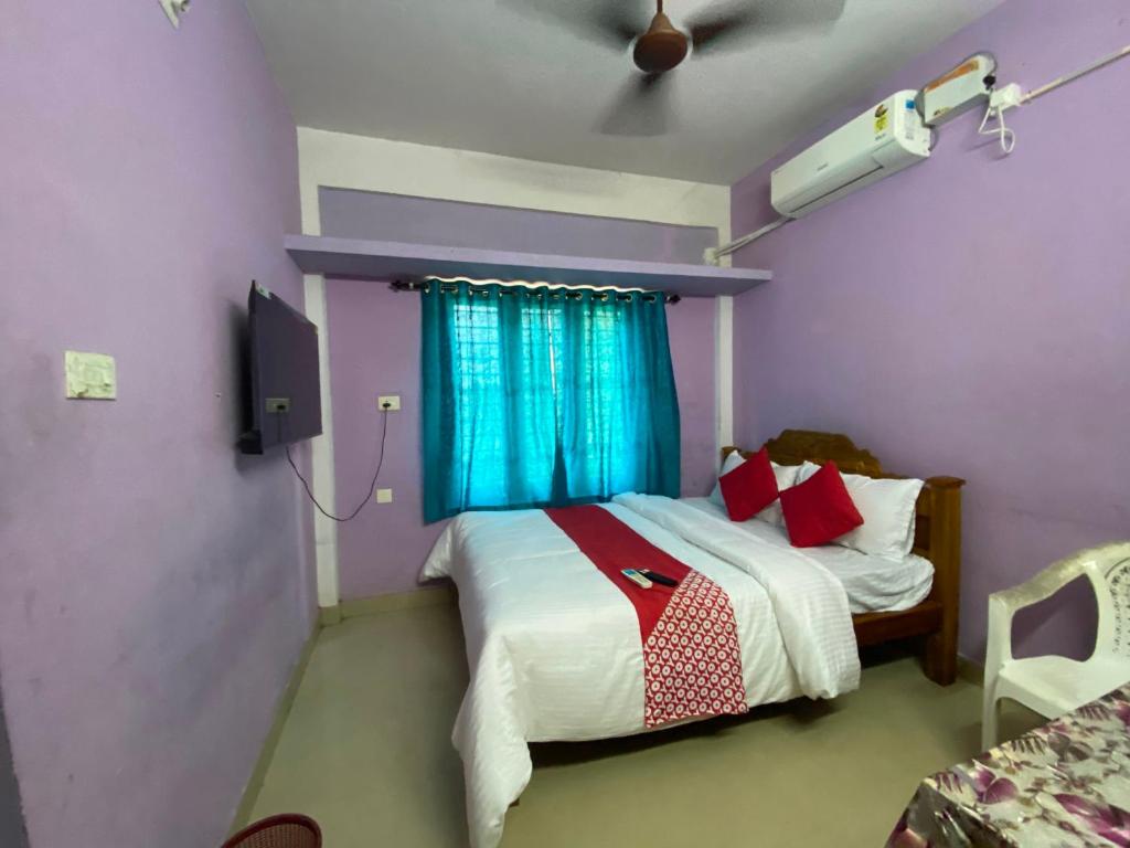 Un dormitorio con una cama y un televisor. en Hotel O Siva Karthika, en Trivandrum