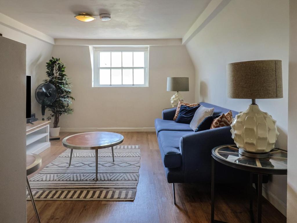 a living room with a blue couch and a table at Sea Holly in Lyme Regis