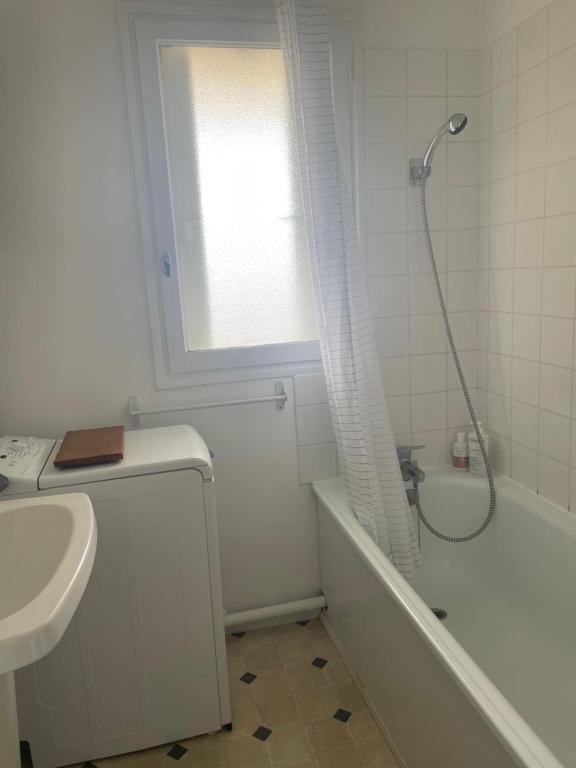 une salle de bain blanche avec une douche et un lavabo dans l'établissement Appartement cosy cabourg, à Cabourg