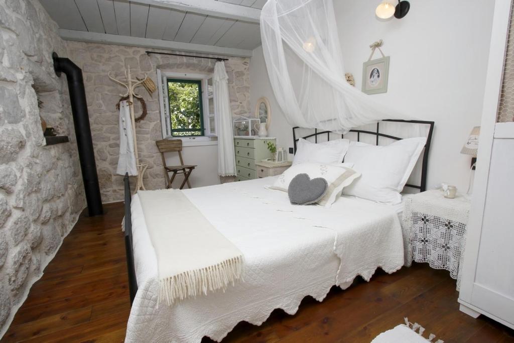 ein Schlafzimmer mit einem weißen Bett und einer Steinwand in der Unterkunft Stone cottage Lavandula in Baška Voda