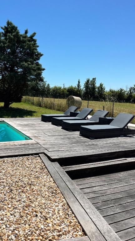 une rangée de lits assis sur une terrasse à côté d'une piscine dans l'établissement Villa Jourdain, à La Genétouze