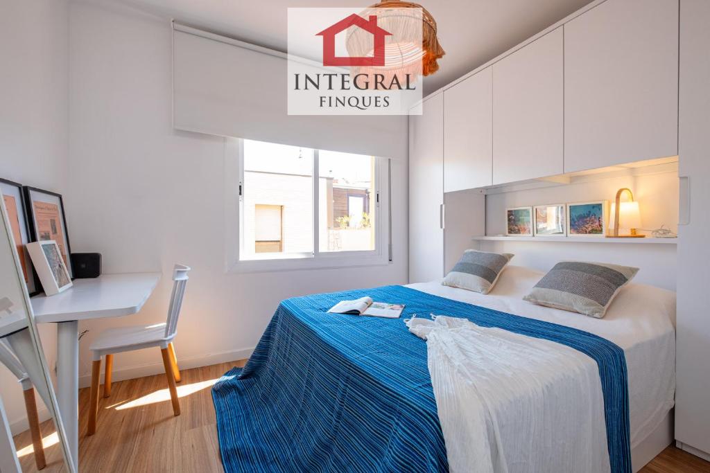 a bedroom with a bed with a blue blanket and a desk at El Refugi de Mar in Palamós