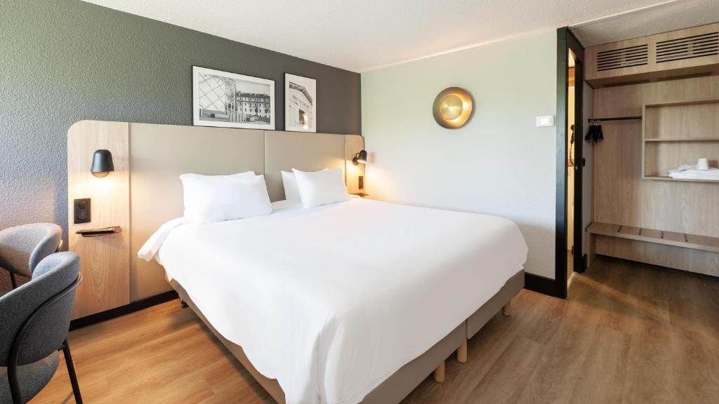 Una gran cama blanca en una habitación de hotel. en Campanile NATURE - Mont de Marsan, en Mont-de-Marsan