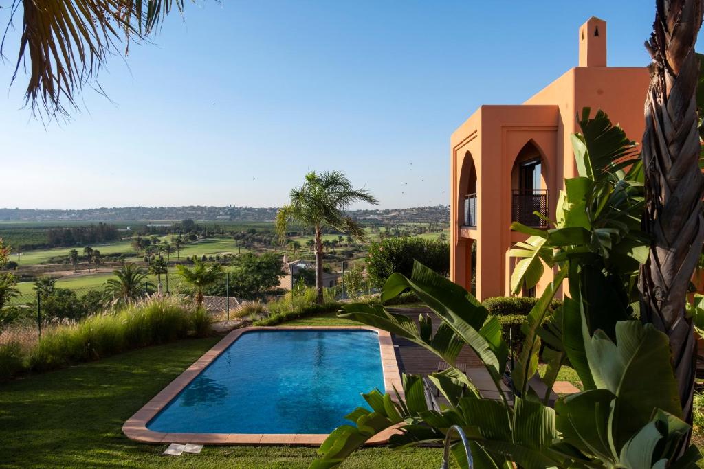 a villa with a swimming pool in front of a house at Amendoeira Golf Resort in Armação de Pêra