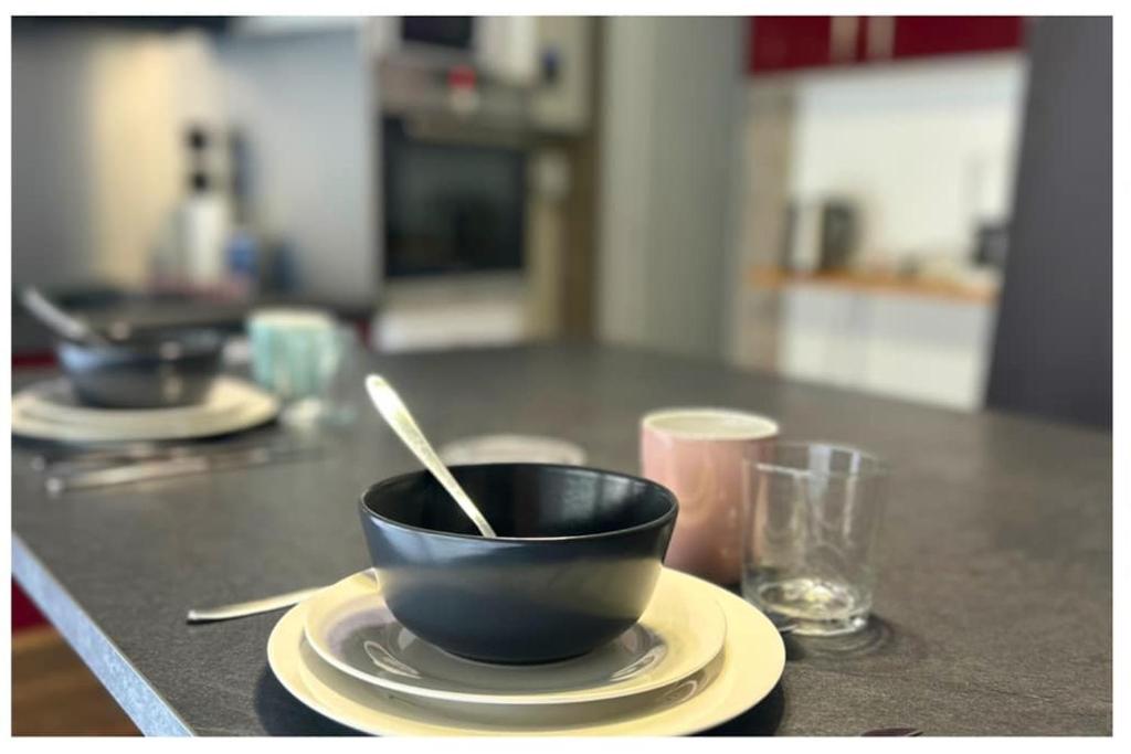 un bol noir sur une assiette avec une cuillère sur une table dans l'établissement Le Fontenoy T2 Tarbes centre ville Brauhauban, à Tarbes