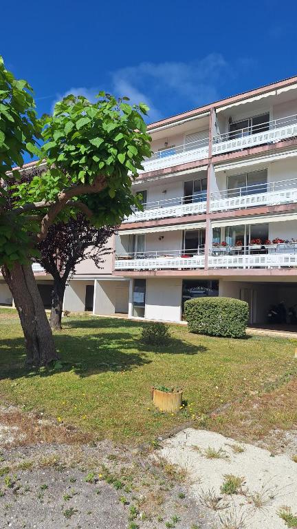 un grand bâtiment avec un arbre devant dans l'établissement Grand T3 entrée Arcachon rénové, à Arcachon