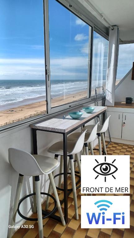 - une salle à manger avec une table et des chaises ainsi qu'une plage dans l'établissement Le Mathgo, à Saint-Hilaire-de-Riez