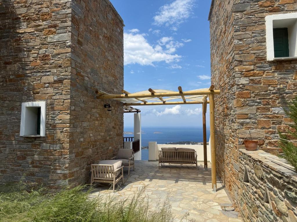 a stone wall with a patio with a pergola at Andros memories in Batsi
