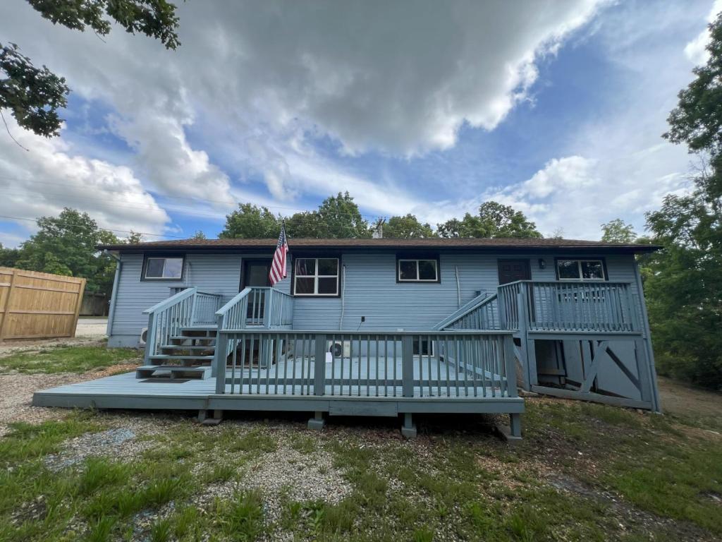 a blue house with a porch and an american flag at Bluebird Liberty Cottage in Saint Robert