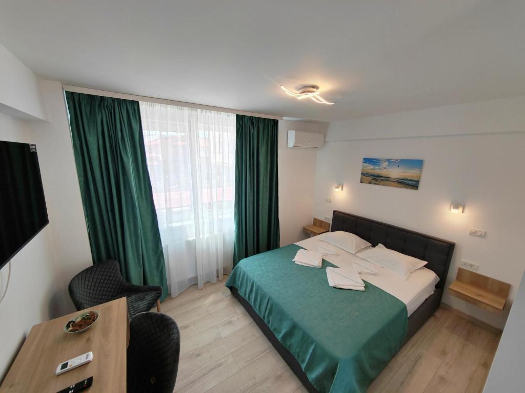 a hotel room with a bed with a green bedspread at Casa BEYAZ in Mangalia