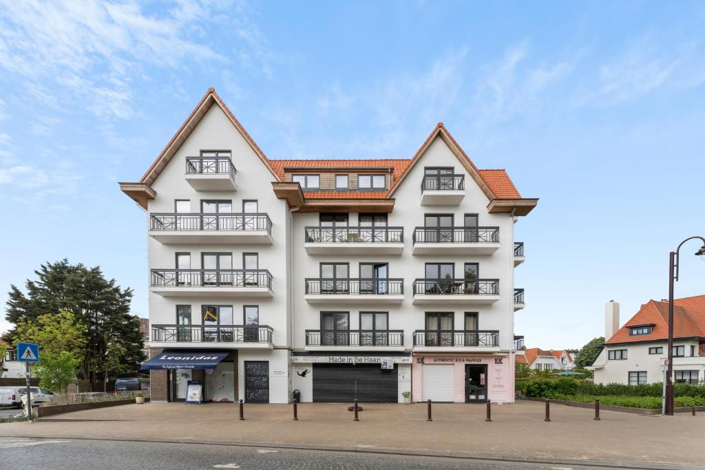Un edificio blanco con ventanas y balcones en una calle. en Hotel Van Brugge D2, en De Haan