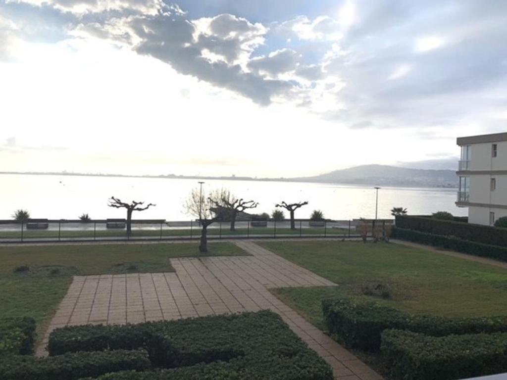 un parc avec vue sur l'eau et un bâtiment dans l'établissement Charmant T1 à Balaruc-les-Bains avec balcon, animaux admis - FR-1-503-76, à Balaruc-les-Bains