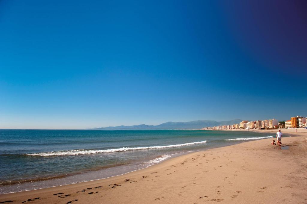une plage avec deux personnes et l'océan et les bâtiments dans l'établissement Appart 5 personnes proche de la mer, à Canet