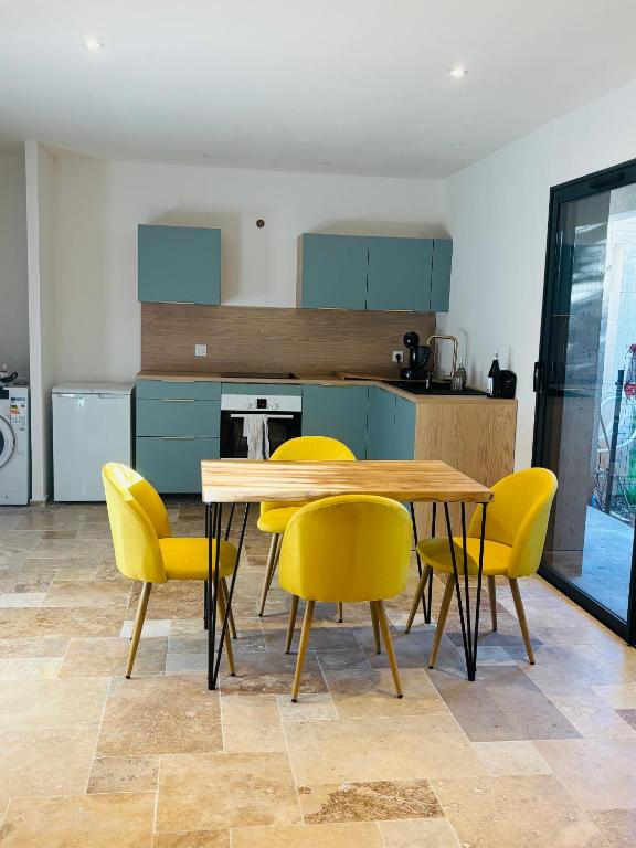 une cuisine avec une table en bois et des chaises jaunes dans l'établissement Maison à 10m de Porto Vecchio centre, à Sotta