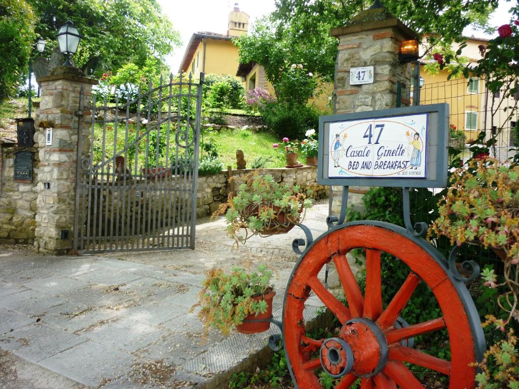 a sign in front of a gate with a wooden wheel at B&B Casale Ginette in Incisa in Valdarno