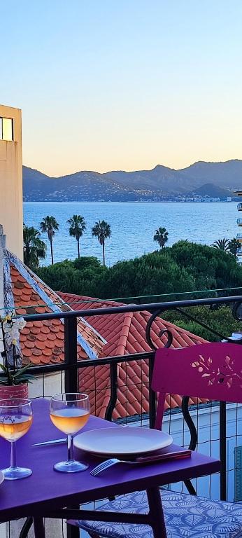 - une table avec deux verres à vin sur le balcon dans l'établissement Belle vue mer, à Cannes