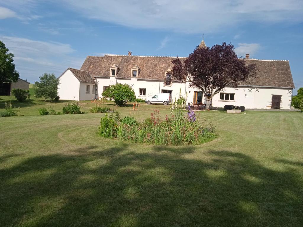 une grande maison blanche avec un arbre dans la cour dans l'établissement le verger 16km du circuit du Mans 8 min de l'autoroute, à Parigné-lʼÉvêque