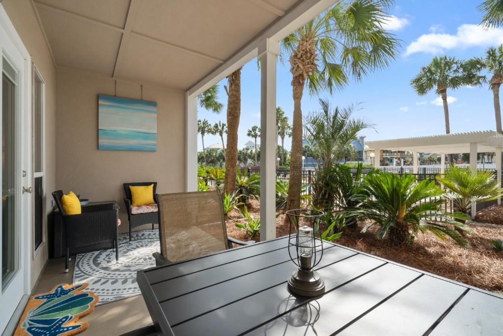 eine Terrasse mit einem Tisch, Stühlen und Palmen in der Unterkunft Grand Caribbean East Poolside Palms in Pensacola