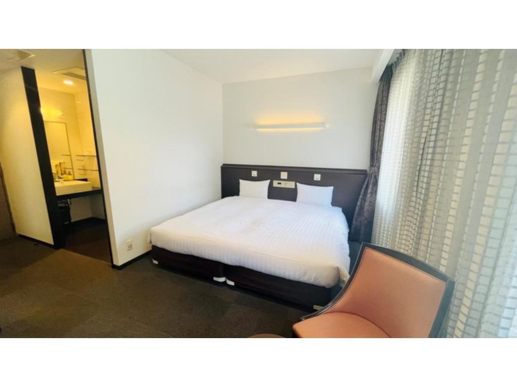 a bedroom with a bed and a chair in it at Midosuji Hotel - Vacation STAY 41579v in Osaka