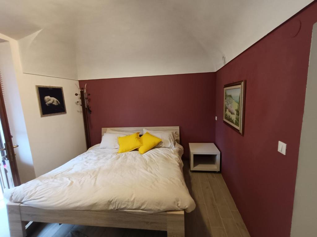 een kleine slaapkamer met een bed met gele kussens bij La petite maison Soleil in Biella