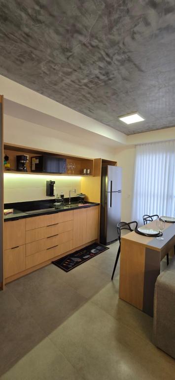 a kitchen with a table and a refrigerator at Ap Familiar Completo luxo Id Vida Urbana in Goiânia