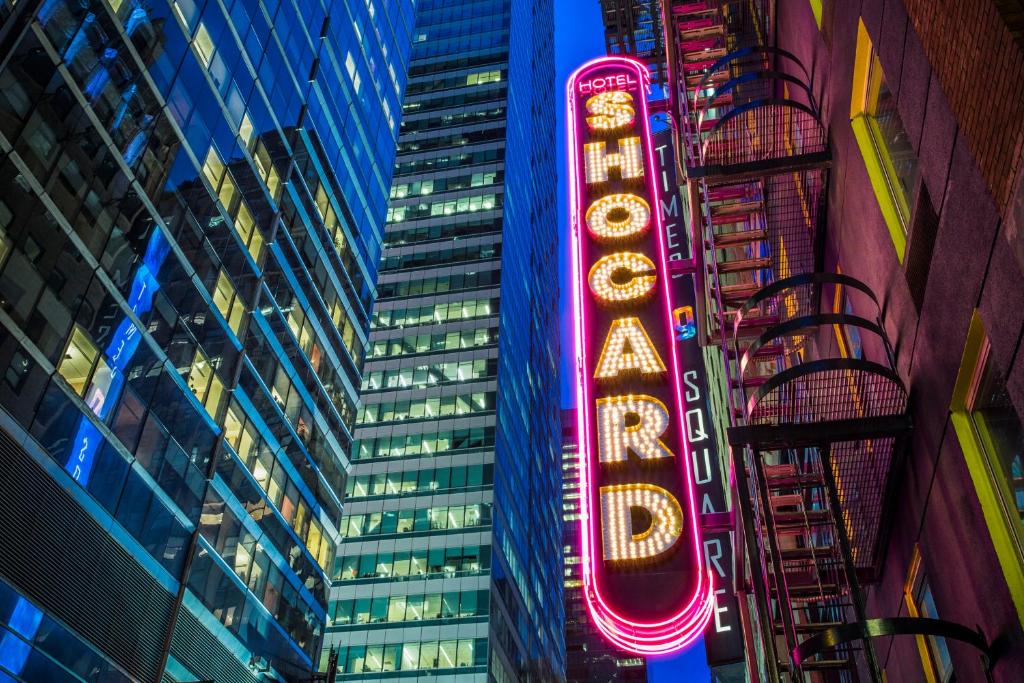 una señal de neón en medio de un edificio alto en Hotel Shocard Broadway, Times Square, en Nueva York