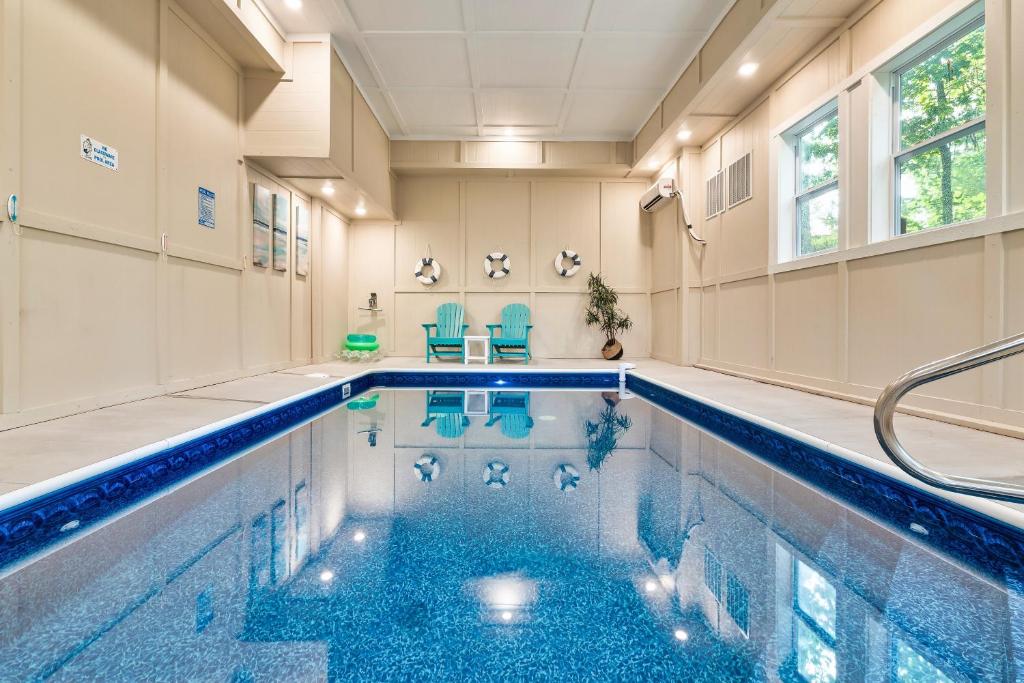 ein Swimmingpool in einem Haus mit blauen Stühlen in der Unterkunft Wink Bear Lodge by Venture Smoky Mountains in Gatlinburg