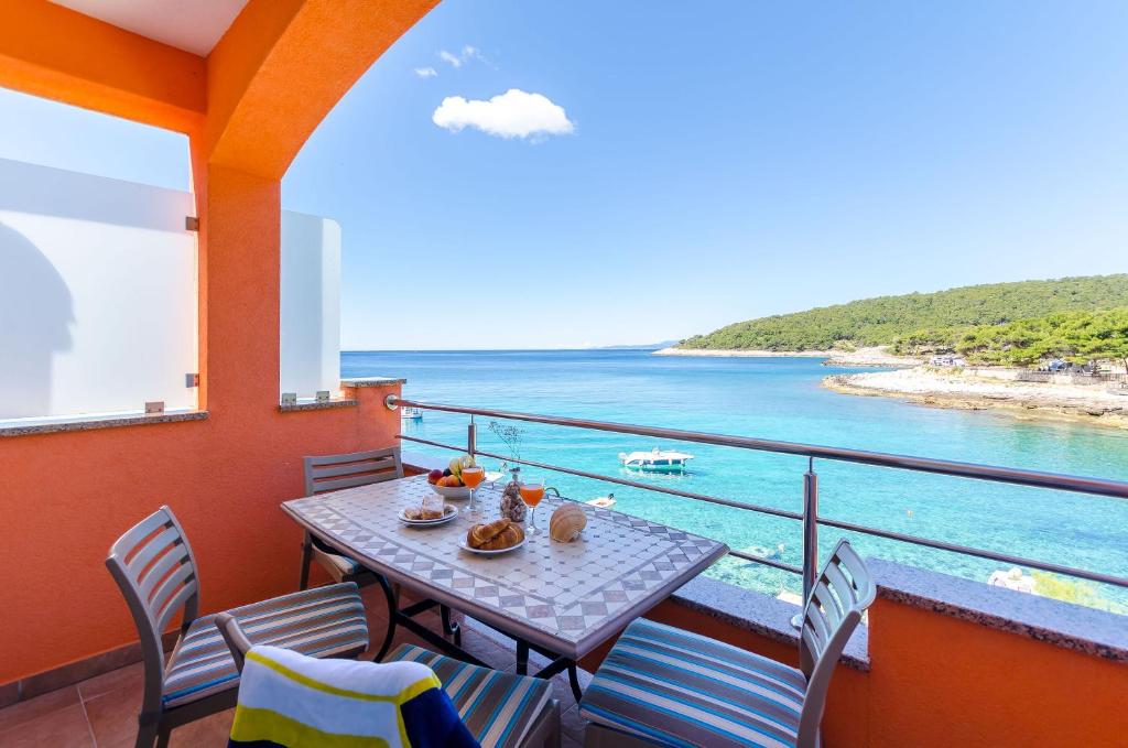 a balcony with a table and chairs and the ocean at Apartments Juka in Milna