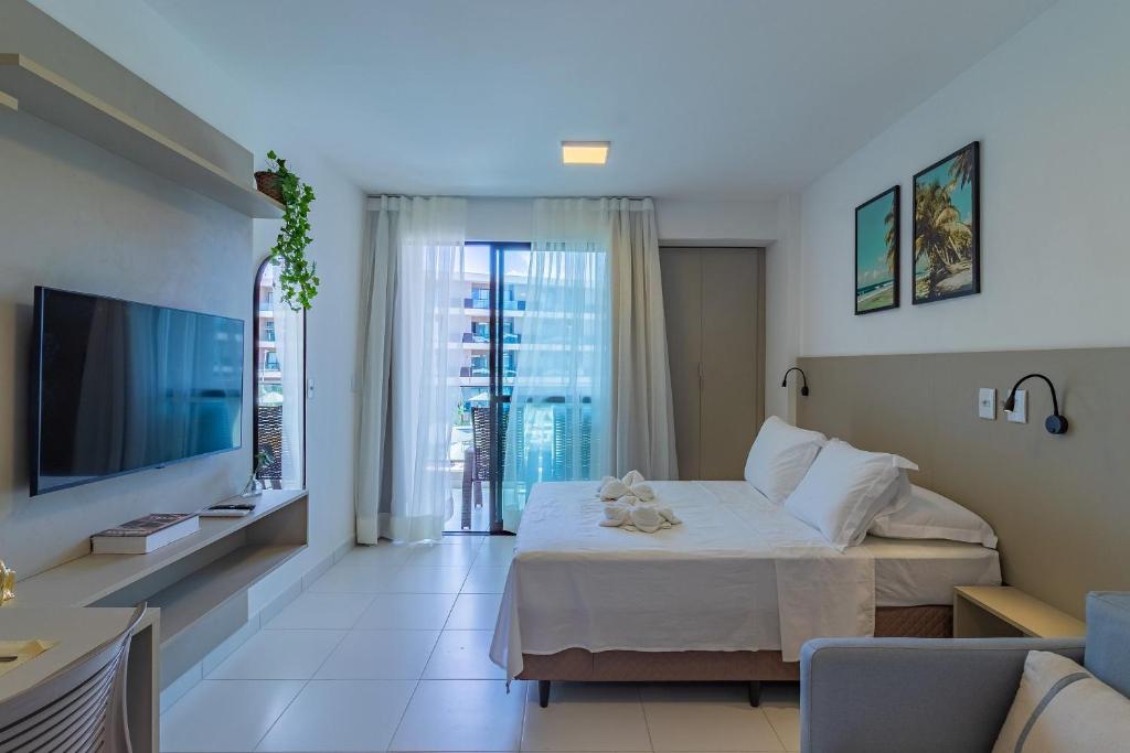 ein Hotelzimmer mit einem Bett und einem Fernseher in der Unterkunft Malia Beach #D105 - Muro Alto por Carpediem in Ipojuca