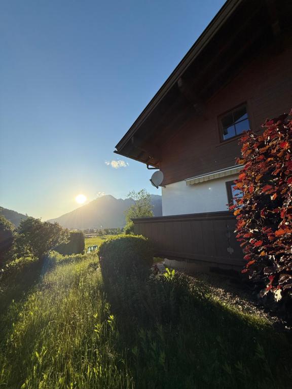 a house on a hill with the sun in the background at Lisa & Gretl's Alpen-Panorama Chalet Saalfelden - 10 Min nach Zell am See in Saalfelden am Steinernen Meer