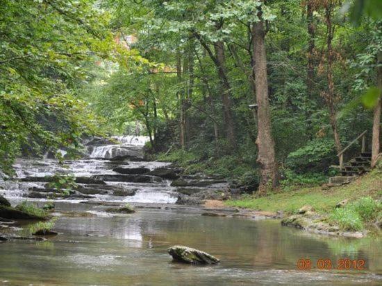 a river with a waterfall in a forest at Waterfalls Edge by Venture Smoky Mountains in Pigeon Forge