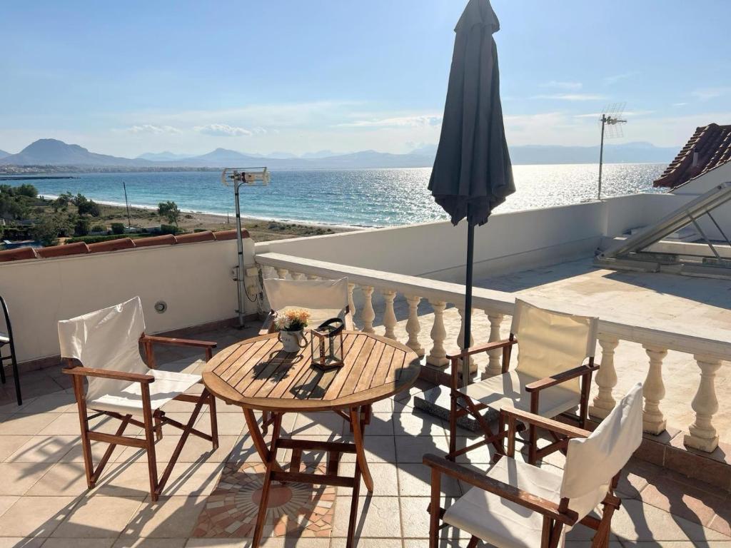 a table and chairs on a balcony with an umbrella at Villa Celine Loutraki in Loutraki