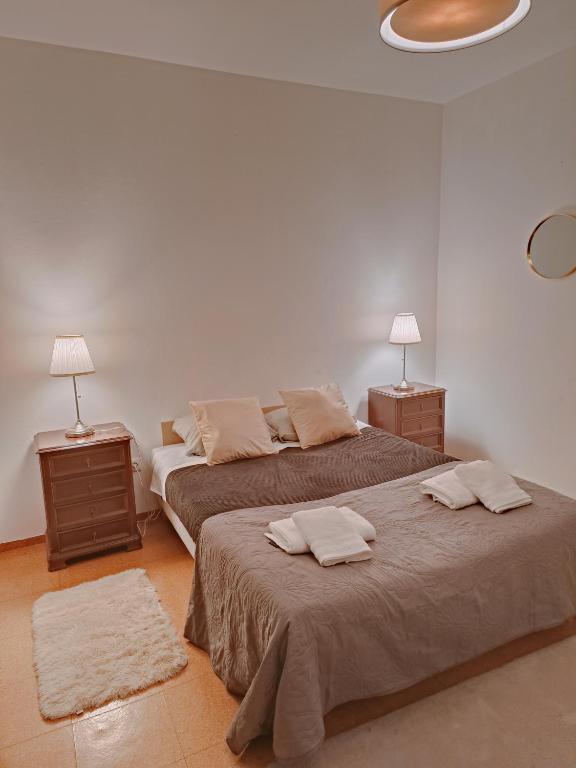 two beds in a white room with two lamps at Casa do Cruzeiro - Favaios in Favaios