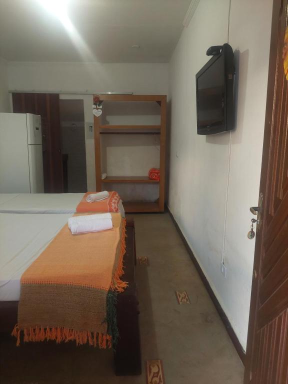 a bedroom with a bed and a tv on the wall at Pousada La Civetta - Maresia in São Sebastião
