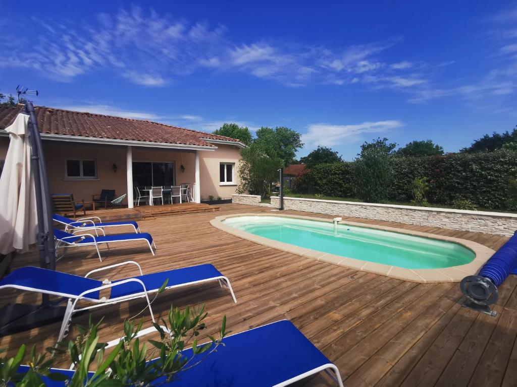 - une piscine avec des chaises bleues sur une terrasse en bois dans l'établissement villa near ocean with swimming pool, à Bias